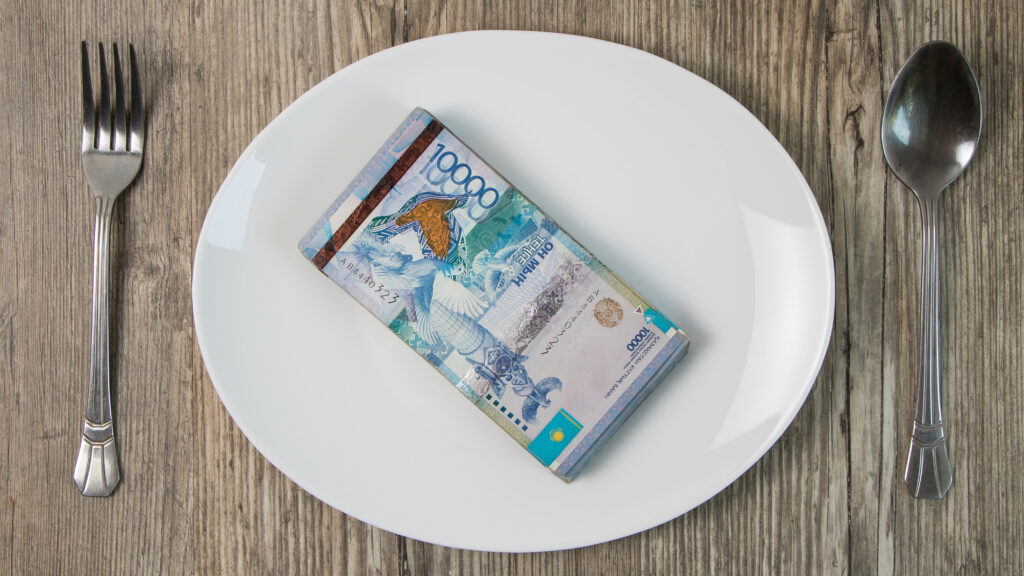 A lot of Kazakhstan tenge on a white plate.The national currency of Kazakhstan.Salary in tenge.Count the money in tenge.Grocery basket, budget savings.Divide the budget.Kazakhstan banks and loans