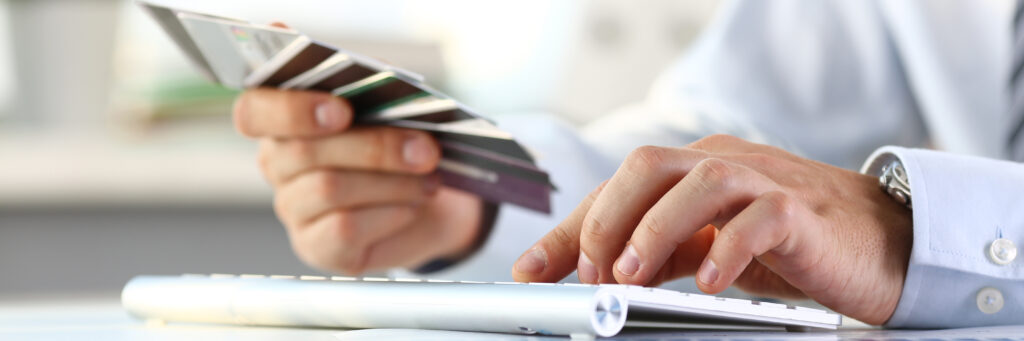 Male arms hold bunch of credit cards and making online purchase using pc closeup. Web order delivery anti-fraud crime software and financial security pin code prosper participation concept