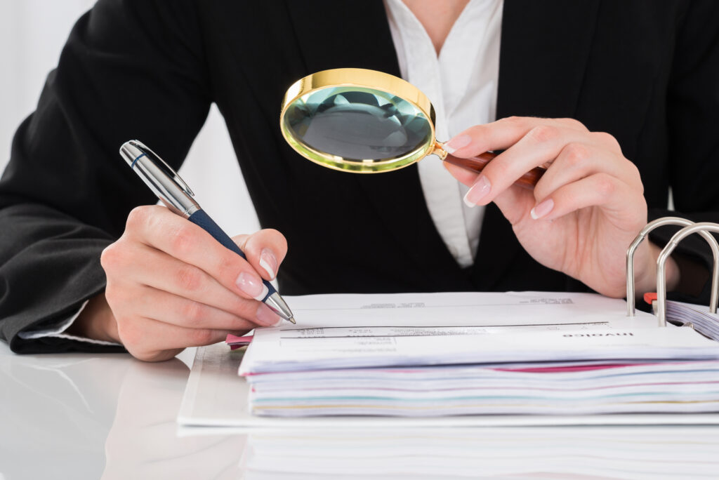 Close-up Of Auditor Inspecting Financial Documents At Desk