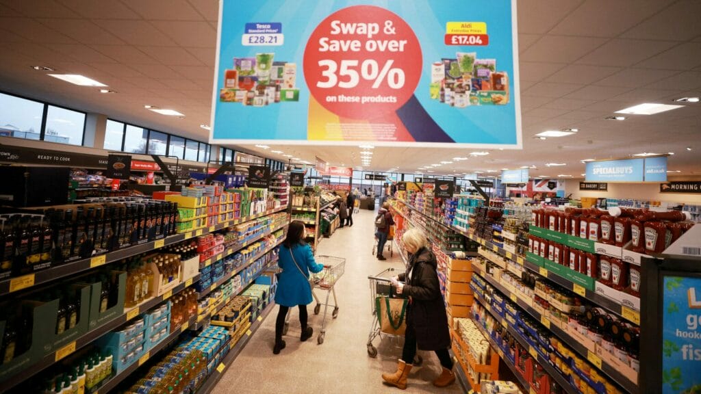 FILE PHOTO: Shoppers push trolleys along an aisle inside an ALDI supermarket near Altrincham, Britain, February 20, 2023. REUTERS/Phil Noble/File Photo