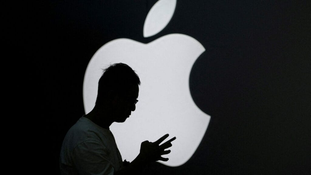 FILE PHOTO: A man check his phone near an Apple logo outside its store in Shanghai, China September 13, 2023. REUTERS/Aly Song/File Photo