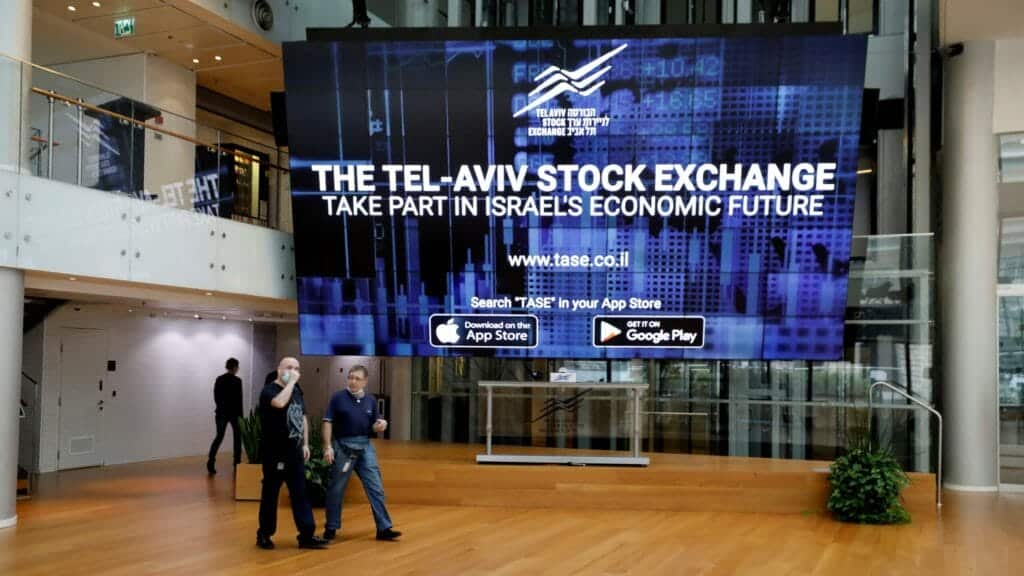 FILE PHOTO: Men walk past an electronic board at the Tel Aviv Stock Exchange, in Tel Aviv, Israel November 4, 2020. Picture taken November 4, 2020. REUTERS/Amir Cohen/File Photo