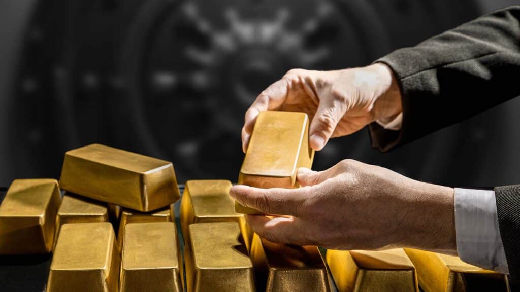Banker's hands, bank vault manager holding a gold bar, gold holdings concept. Savings and investments, business and finance
