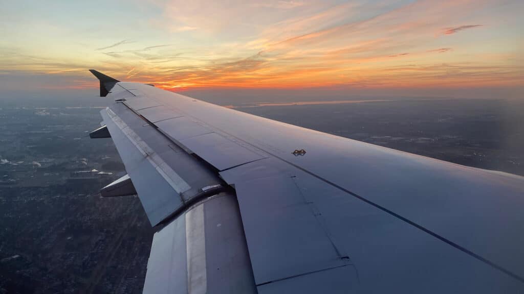 Plane ride window seat with wing and beautiful view of sky and clouds sunset and snow