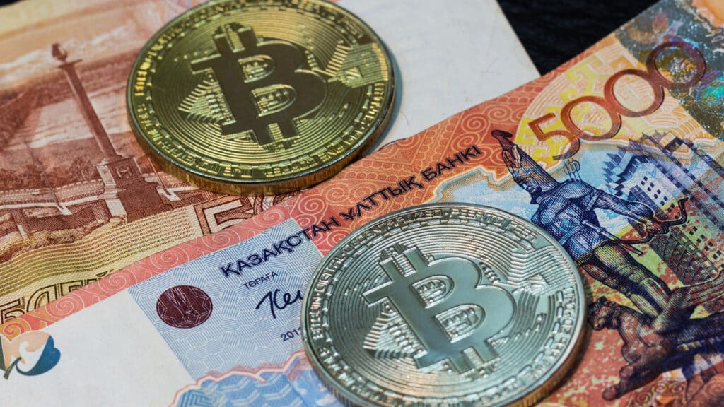 Physical coins of crypto currency. Silver and gold bitcoins on five thousand banknotes of Russia and Kazakhstan.