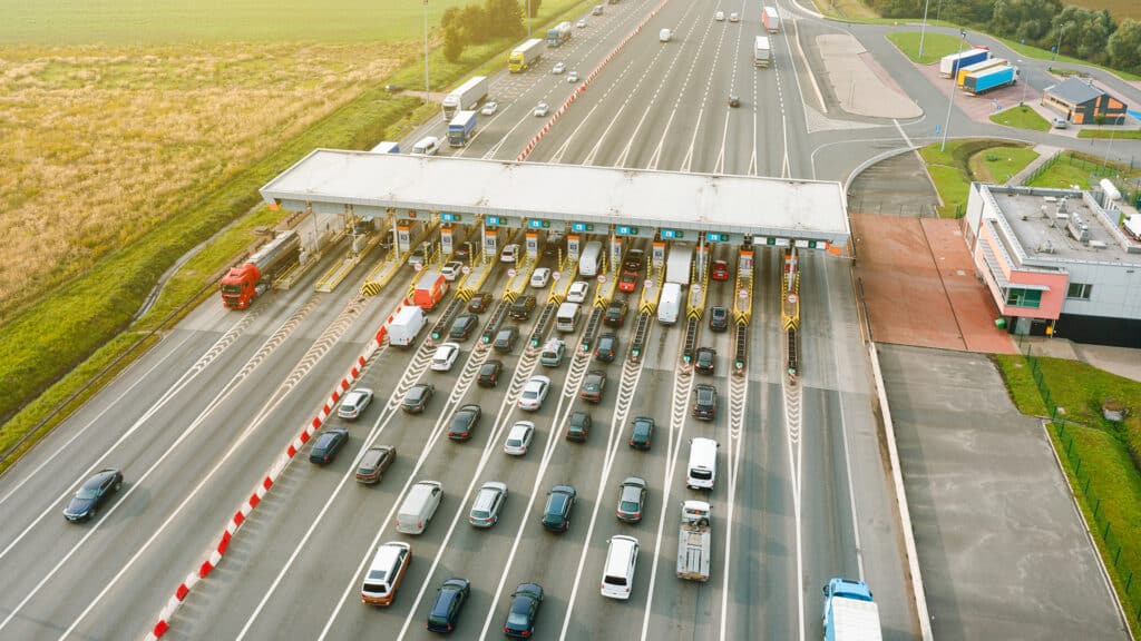 An overhead view of a busy toll road with many cars queuing up to pay the highway toll