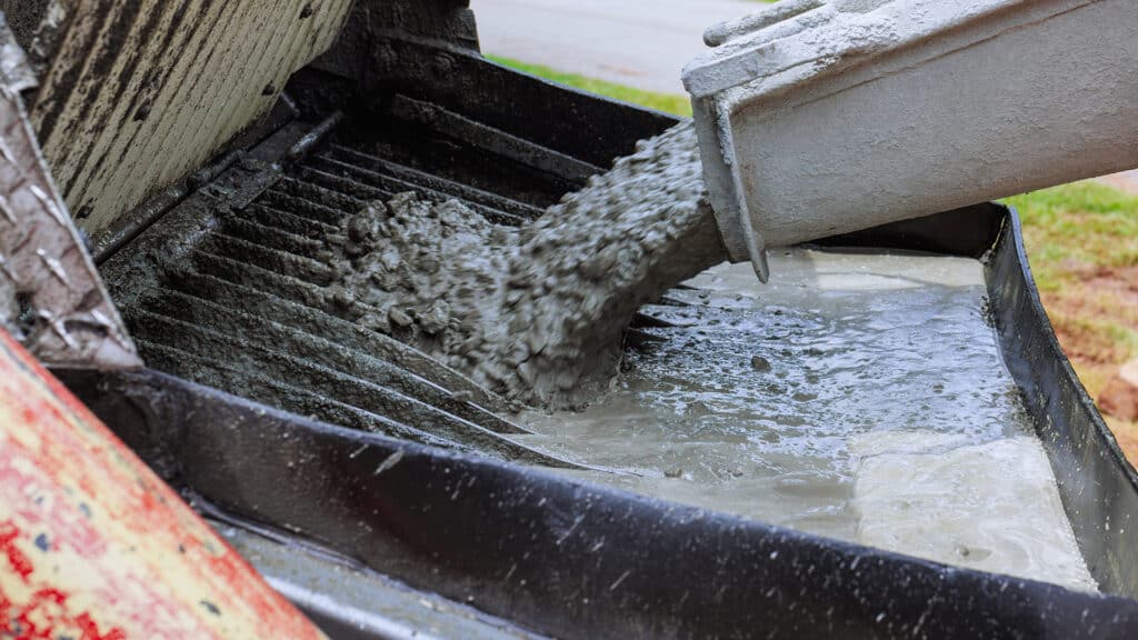 Worker pours fresh concrete into mixer at home construction site during works constructed day