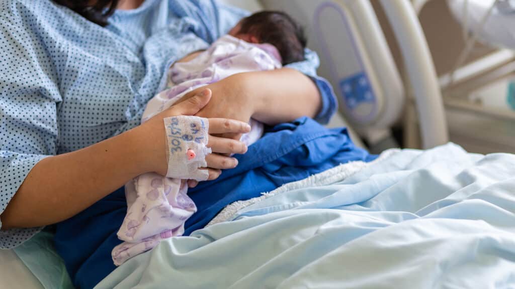 Asia Chinese Mother holding her newborn child after labor in hospital wad room