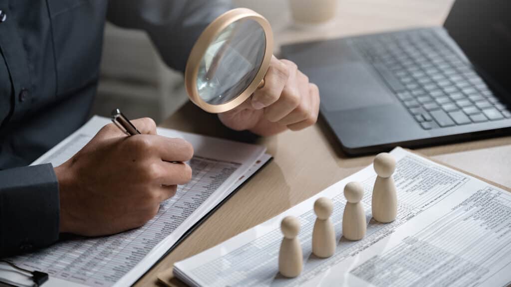 Human resource manage staff team. hr recruitment. Employment Management teamwork. A person is sitting at a desk with a magnifying glass in their hand, writing on a piece of paper.