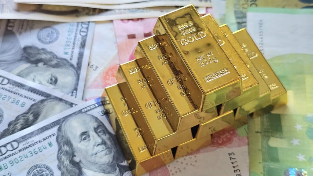 Gold bullion on pile us dollar bills as background. finance and saving concept