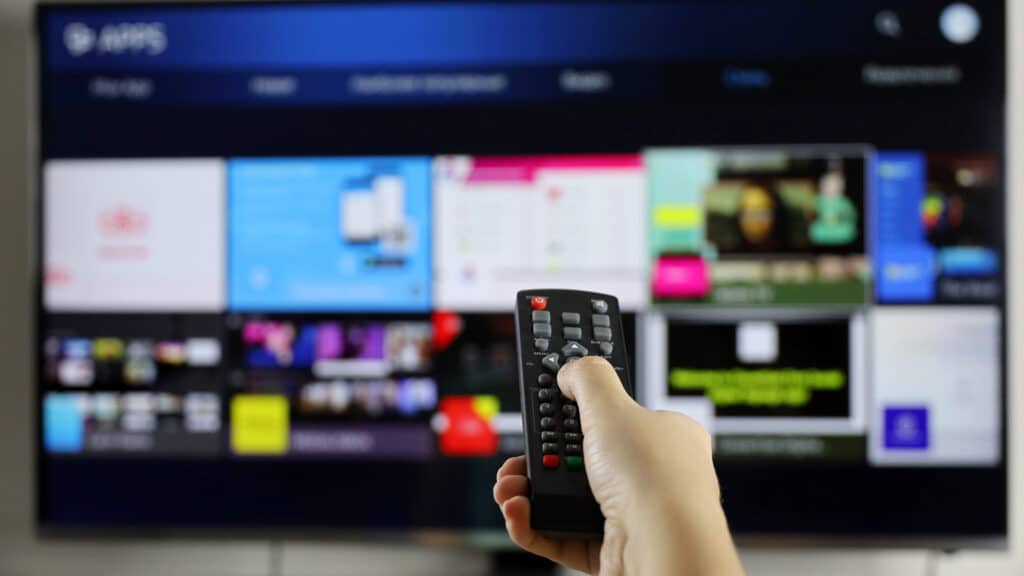 Female hand with remote controller on smart TV screen background. Woman choosing streaming services, watching movies