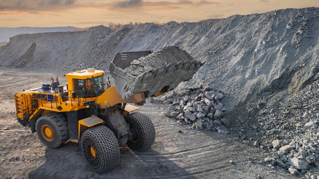 Industrial excavator loader of gold ore to truck, mining industry, Aerial top view.