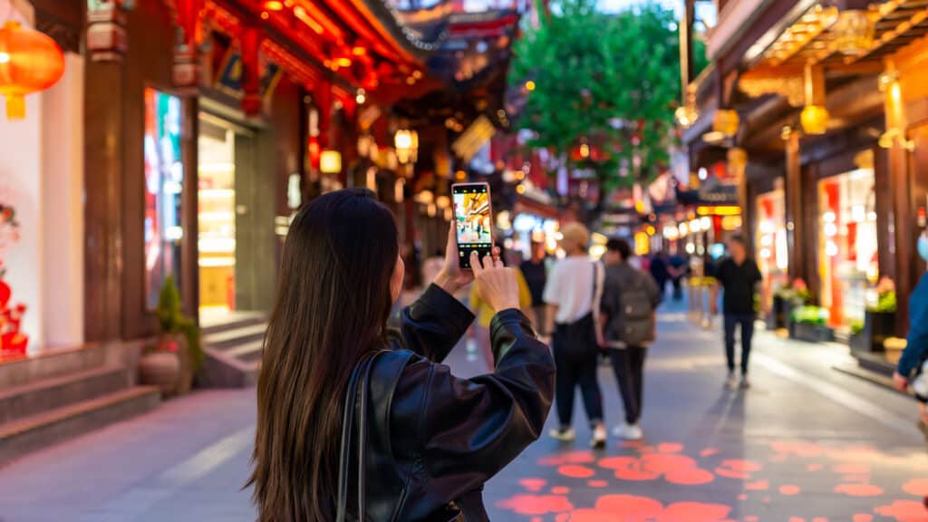 Young female tourist taking a photo of the Yuyuan old street in Shanghai, China