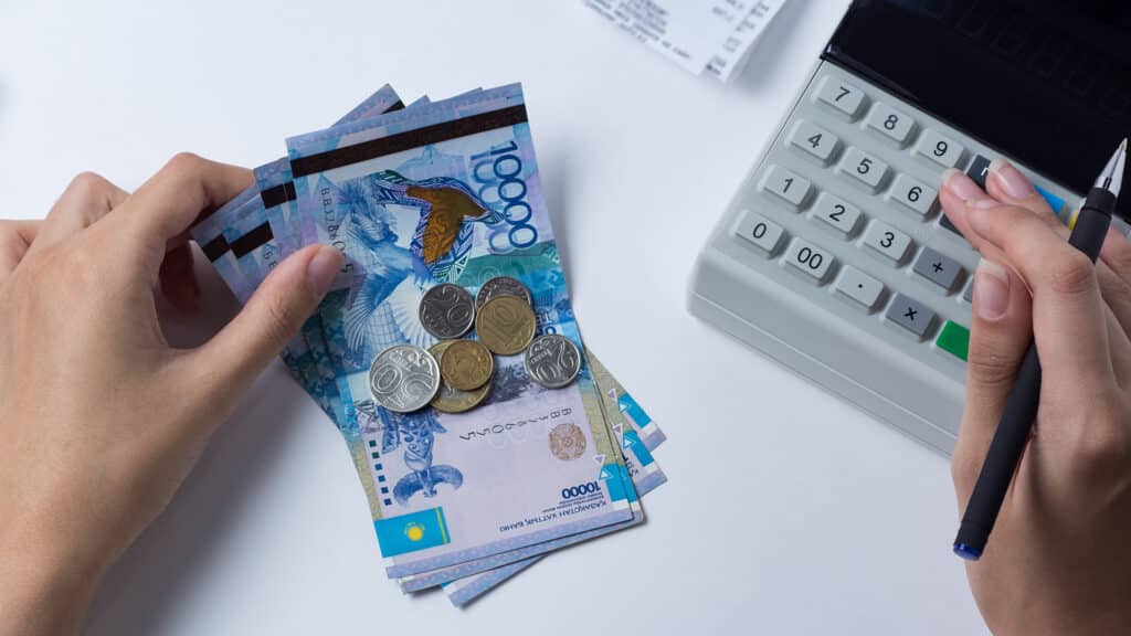 Tenge at the cashier accountant in the hands of the workplace in the office. The cashier counts the money KZT in the workplace in Kazakhstan. Salary in Kazakhstan