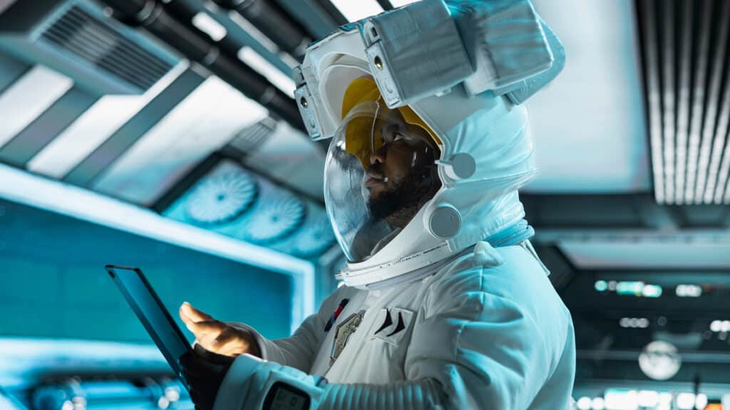 Astronaut wearing helmet doing galaxy observation using tablet during scientific mission in spacecraft. Spaceship cosmonaut in spacesuit monitoring system diagnostics during planetary exploration