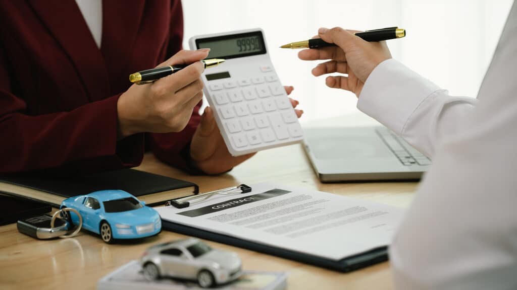 A businessman and client complete an agreement by signing documents for car insurance, loan, or rental, symbolizing finance, contract, policy, investment, purchase, legal paperwork, and secure ownersh