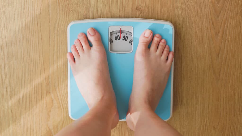 point of view - closeup feet for asian woman measure weight on scale