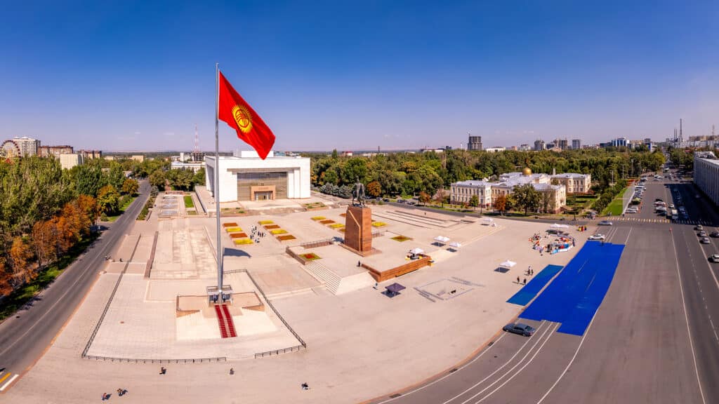 Aerial top view to Flag Kyrgyzstan. Monument Epic Statue of Aykol Manas - kyrgyz hero on Ala-Too Square. State History Museum in downtown of Bishkek city. Central asia,