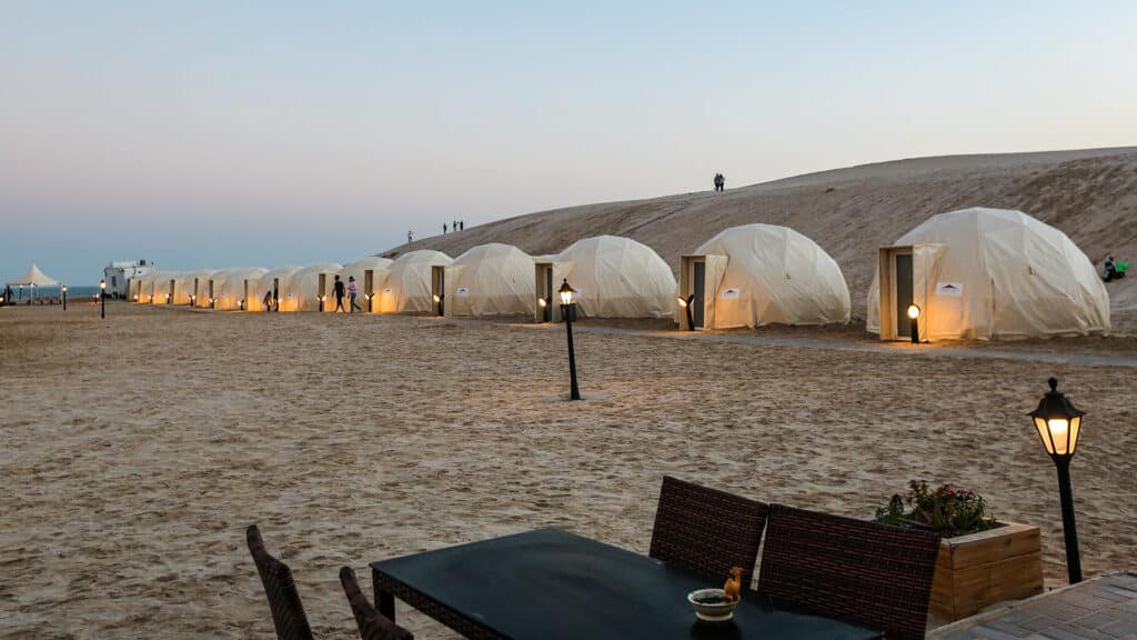 Khor al Udaid, Qatar - February 11, 2022: tents at QIA desert camp at Inland Sea in Persian Gulf at sunset sky. Middle East, Arabian Peninsula. Inland sea is a major tourist destination for Qatar.