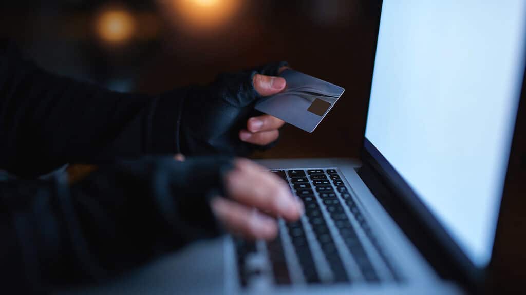 Hacker, credit card and finance on laptop at night by hacking software database, password or security attack for financial information. Criminal, typing and digital banking fraud for privacy risk