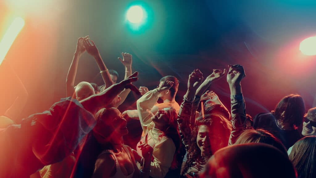 Expressive crowd movement during night music event. Concept of emotional intensity, shared experience, rhythmic freedom, immersive soundscape and Christmas party atmosphere.