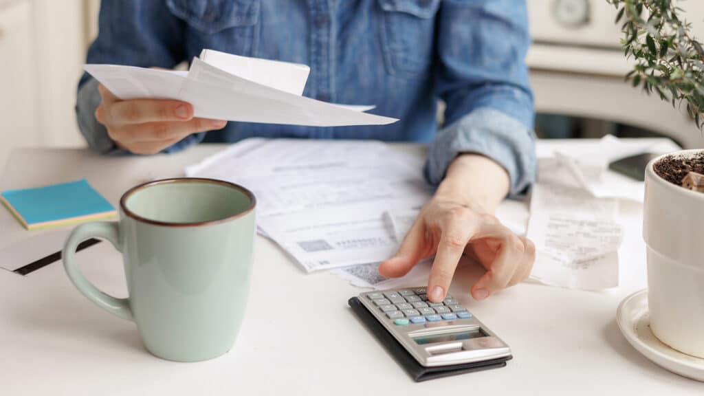 woman pays utility bills and writes checks. a European woman at home makes a calculation of expenses for a month. financial literacy and loan repayment. a woman calculates on the calculator the amount