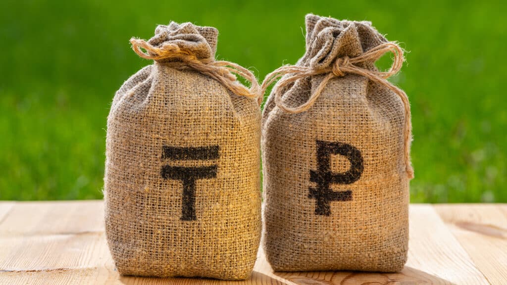 Money bags with symbols of the Russian ruble and the Kazakh currency - tenge