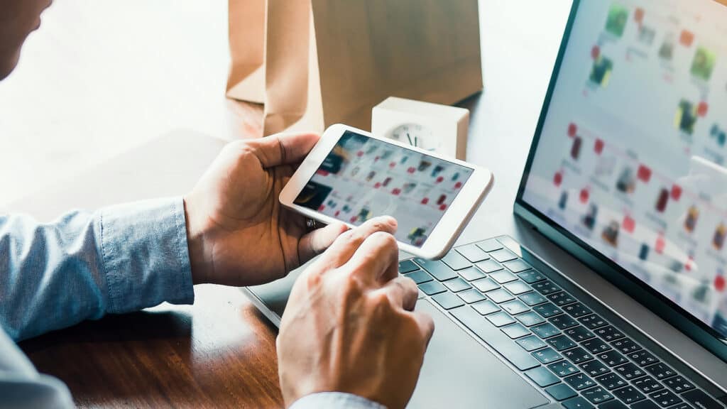 Hands of man are holding smart phones and using laptops computers are entering websites to buy products.
