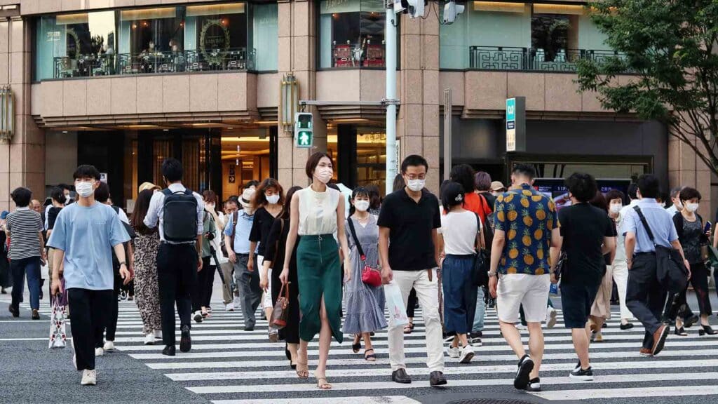 TOKYO, JAPAN - June 29, 2022: Pedestrians using a crosswalk in Ginza in the late afternoon in summer. Mitsukoshi Department Store is in the background.