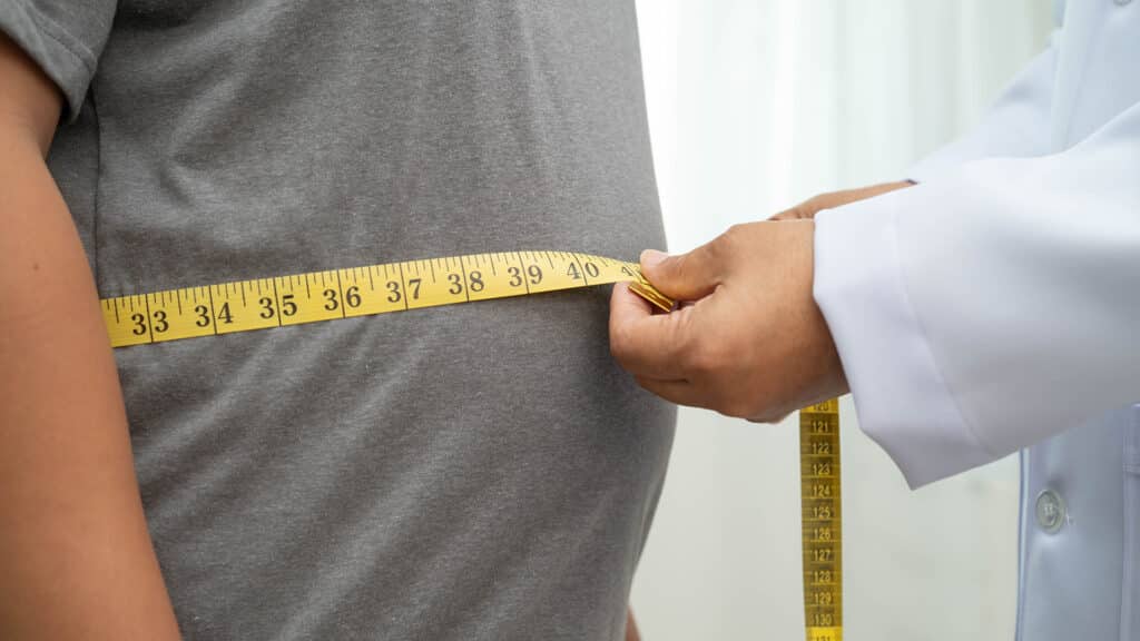Asian woman with fat belly big size overweight and obesity with measure tape.
