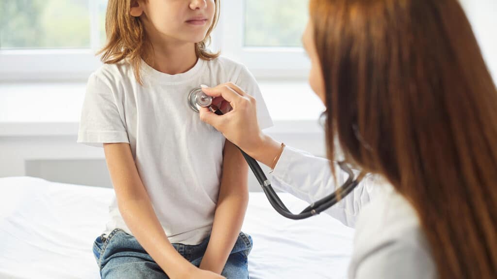 Pediatrician doctor stethoscope listening to kid heart, lung, child health care, clinic checking up exam, kid patient sitting on coach, healthcare hospital professional controlling physical well-being