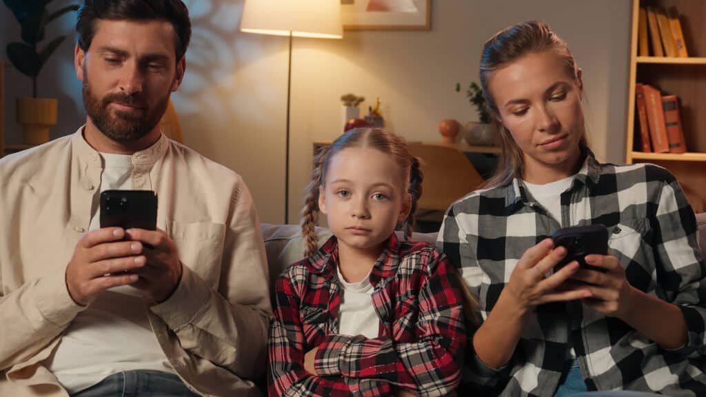 Caucasian family parents mother father using mobile phone smartphones scrolling gadgets addict dependence internet ignore daughter child sad kid girl ask attention lonely problem at evening home night