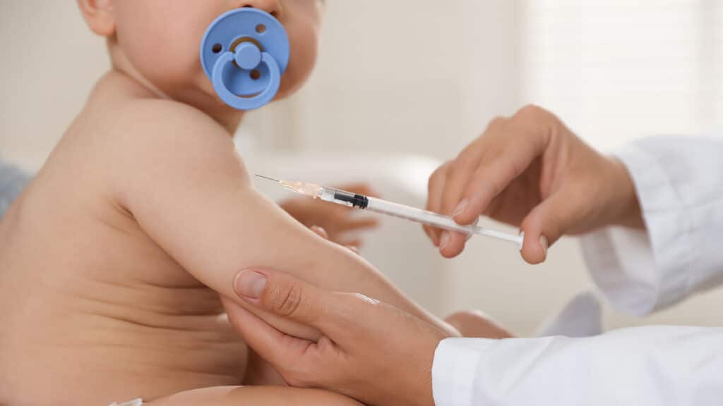 Pediatrician vaccinating little baby in clinic, closeup