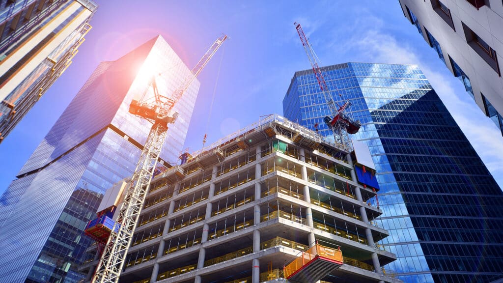 Crane on the construction site in a site surrounded by the high buildings. Office building under construction in the vicinity of high apartment buildings and office building.