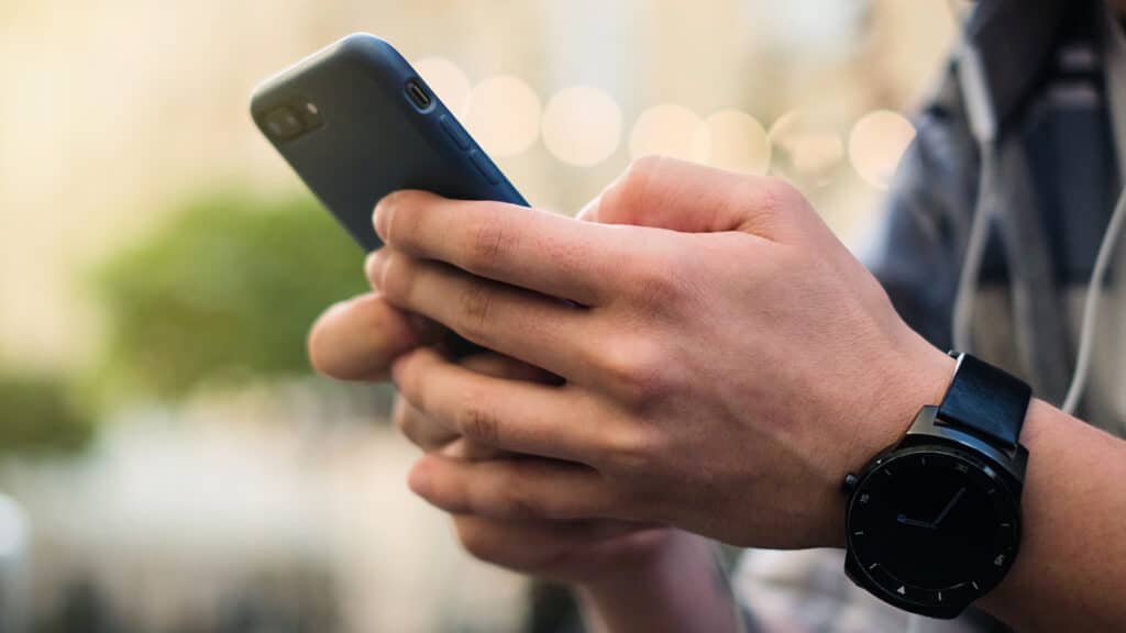 Close up of a man using mobile smart phone outdoor, young man using his mobile phone in city.