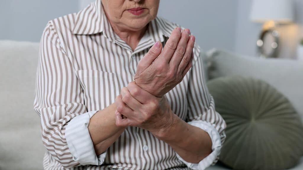 Rheumatism symptom. Senior woman suffering from wrist pain at home, closeup. Space for text